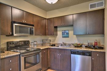 Model home kitchen with brown cabinets, dishwaher, oven/stove and microwave above the stove.at Fountains of Fair Oaks, Fair Oaks, CA